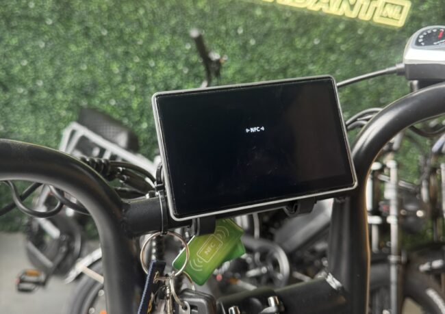 Close-up van het OUXI HC80 fatbike display met NFC-tag die wordt gescand voor beveiliging